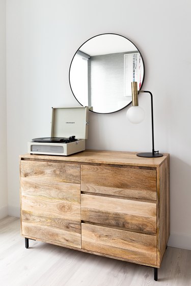 Modern rustic dresser, round mirror, record player, metal and glass lamp